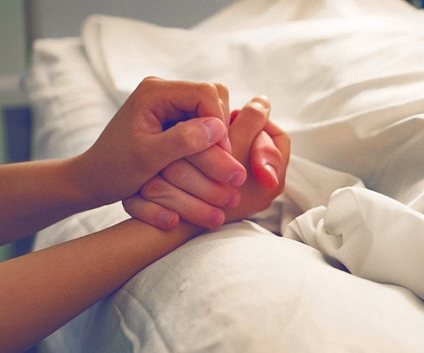 Holding hand of loved one as they pass away in hospital
